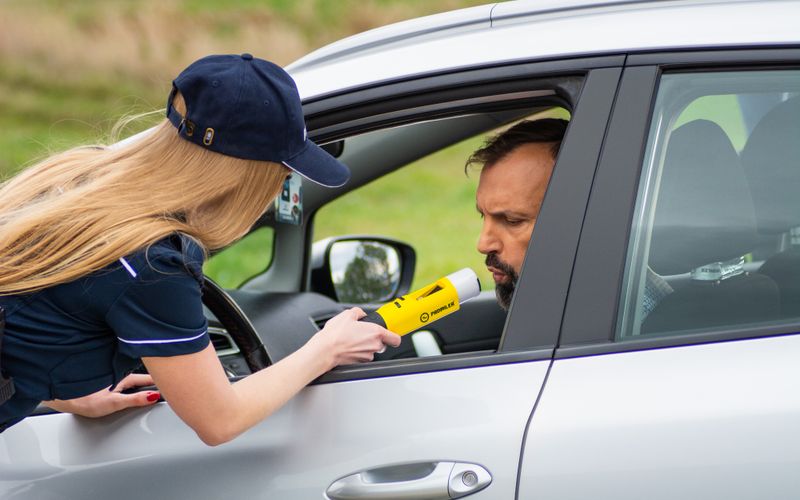 Driver taking a breathalyzer test through the car window