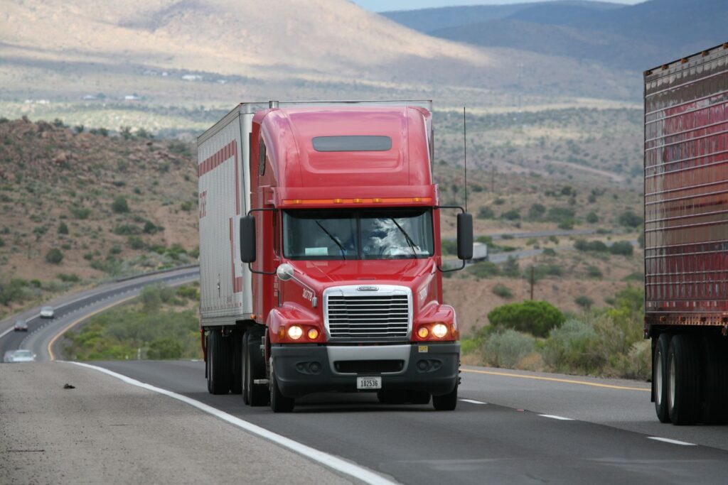 Red semi truck driving on a desert highway