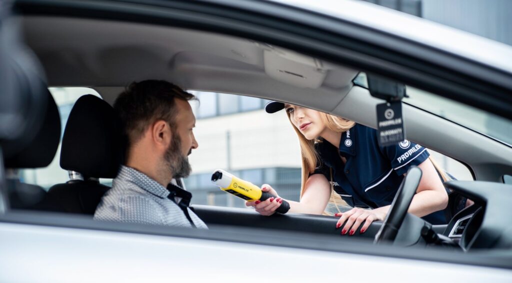 Police officer holding a breathalyzer at a driver window